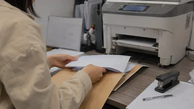 Paperwork being organised beside a printer